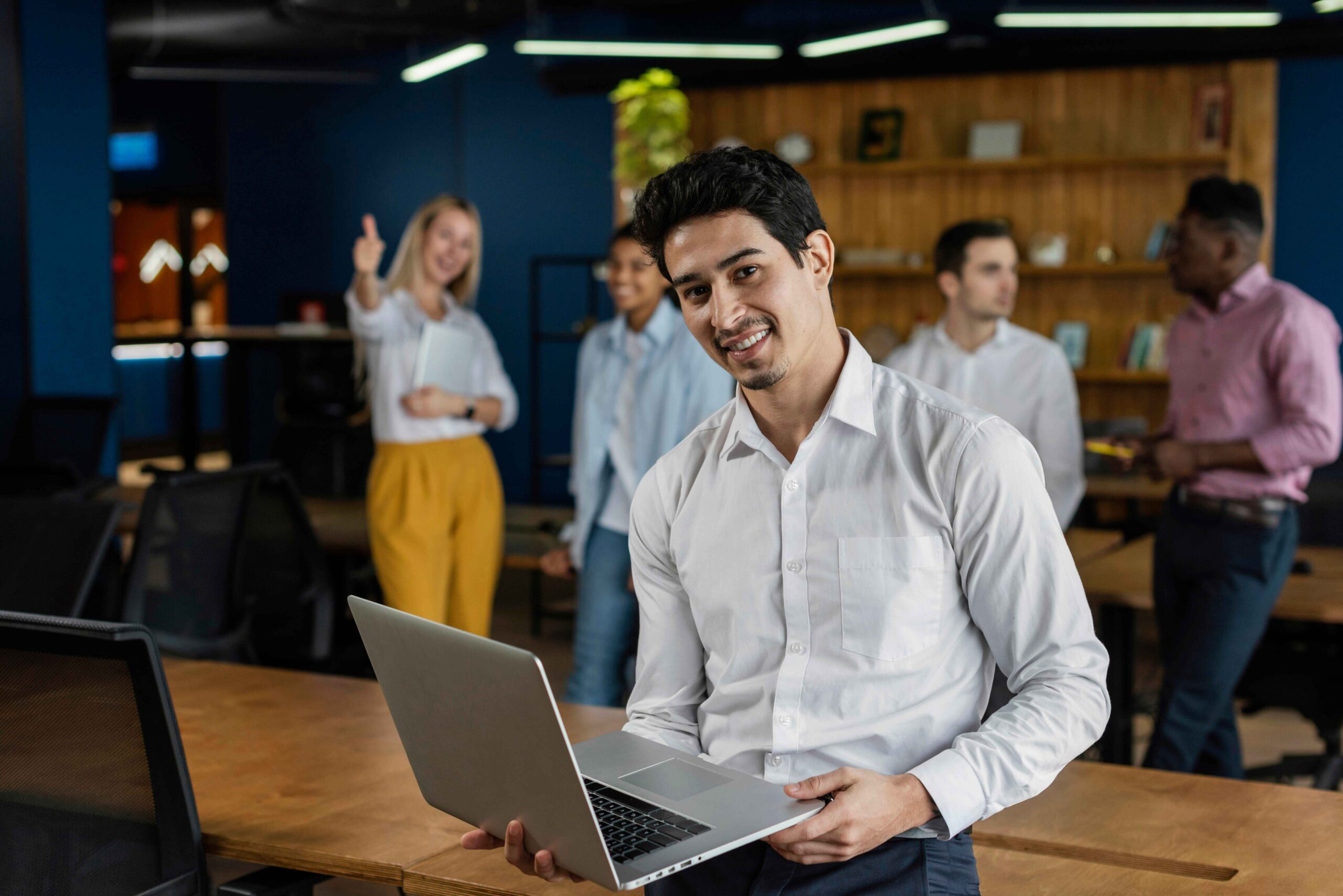 Smiling employee with laptop in modern office, embodying confident employee brand ambassadors teamwork