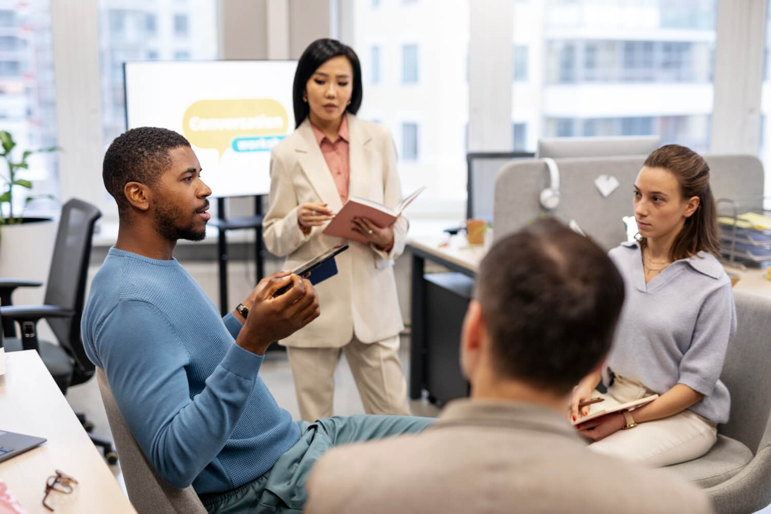 A group of employe advocates sitting around a circle in the office with the back screen having a social icon